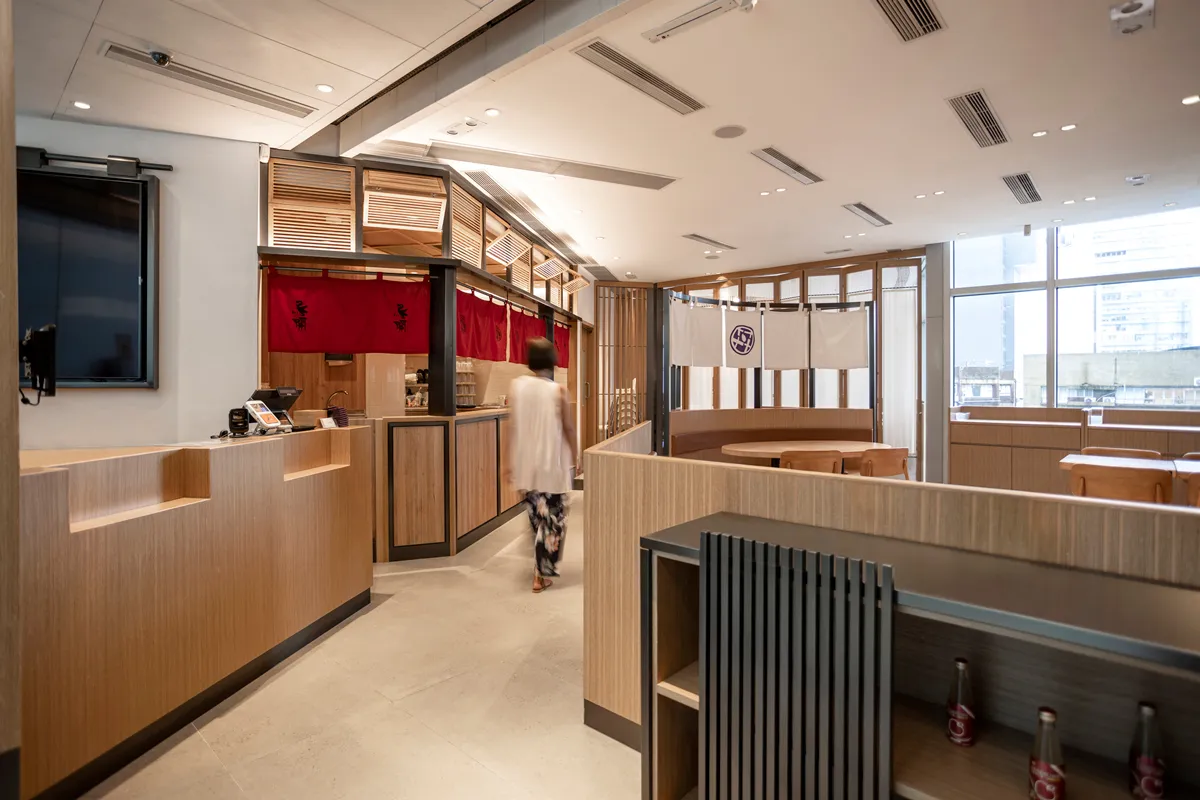 Spacious DONDONYA x TORIKAI eatery showcasing a traditional Japanese bar with Shoji elements and red Noren curtains, seamlessly integrated by Rebel Arkitekt.