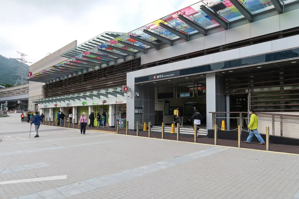 Street-level view of the entrance to a modern railway station with commuters.