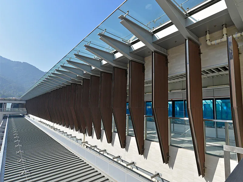 Station exterior with innovative sun-shading louvers against a backdrop of mountains.