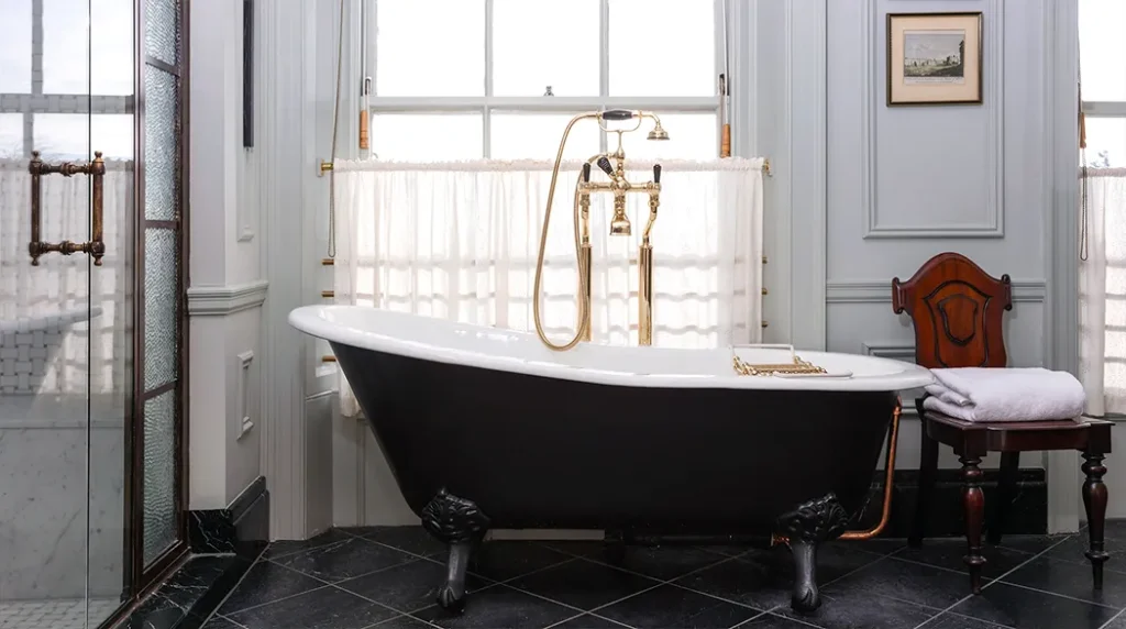 Classic clawfoot bathtub with gold fittings and a privacy curtain in a chic room.