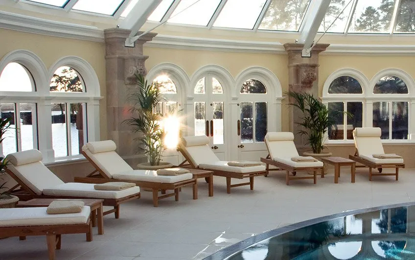 Poolside lounge area with sunlit arched windows and comfortable recliners.