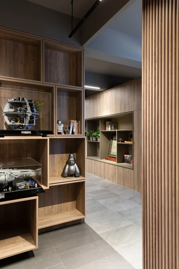 Modern office foyer showcasing custom shelving with accent pieces, featuring wooden textures and sleek lighting that highlight the display and walkway.