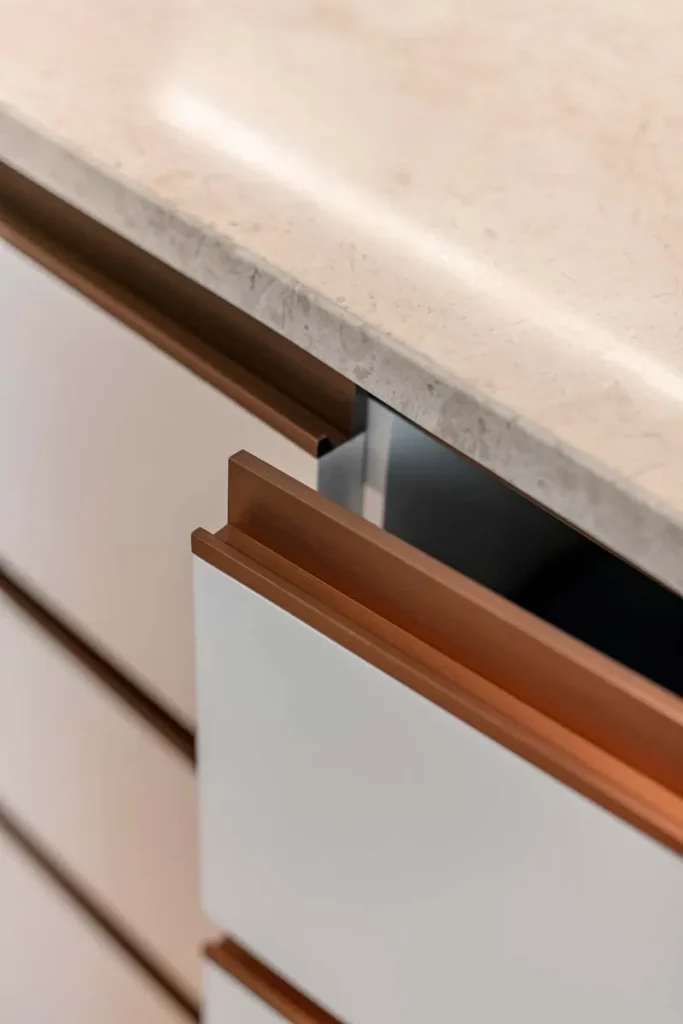 Detail of a bespoke cabinet with light beige marble top and richly finished wooden drawers, showcasing Rebel Arkitekt’s commitment to blending functionality with subtle luxury in interior design.