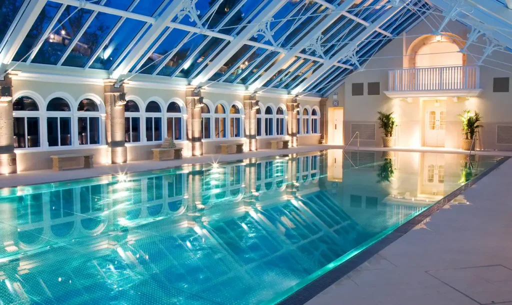 Elegant evening view of a glass-roofed pool with reflections and classical windows.