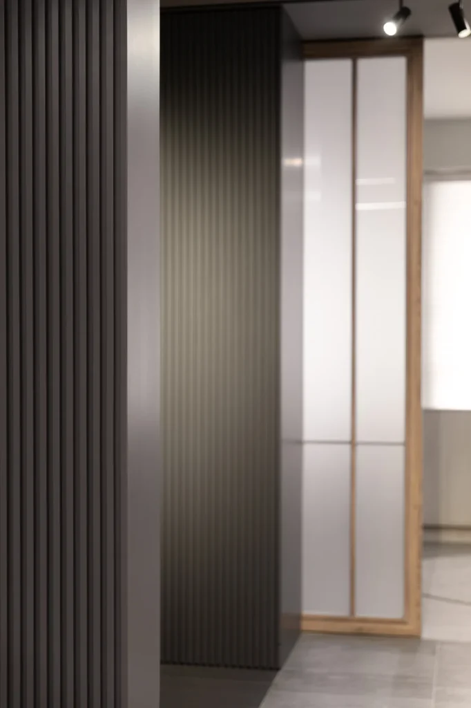 Modern design by Rebel Arkitekt features grey timber slats on a sliding door, blending functionality with an aesthetic that enhances spatial dynamics and privacy in an office setting.