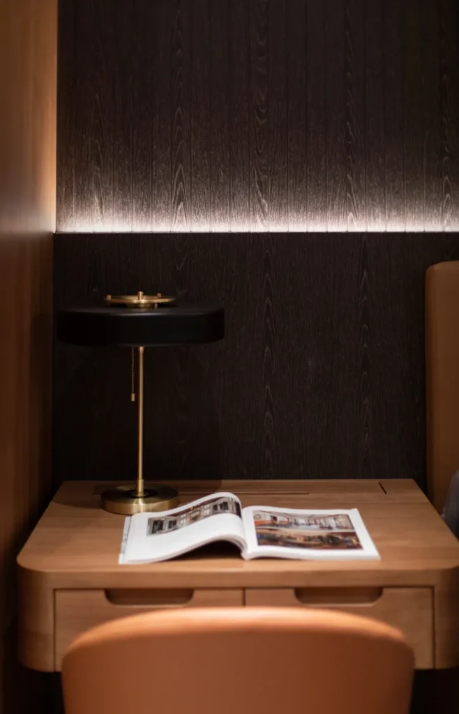 Warmly lit master bedroom bedside scene with a minimalist aesthetic by Rebel Arkitekt, featuring a sleek brass lamp on a walnut nightstand.