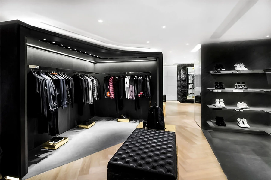 Luxury men's wear section with black themed clothing racks, leather seating, and stylish shoe shelves.