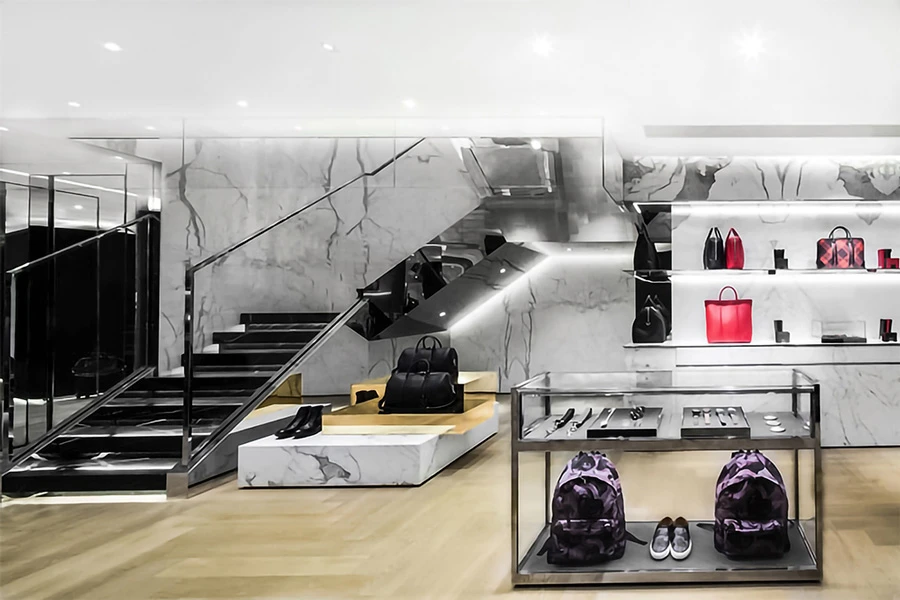 Chic women's luxury store with marble staircase and handbag displays, accented by bold red accessories.