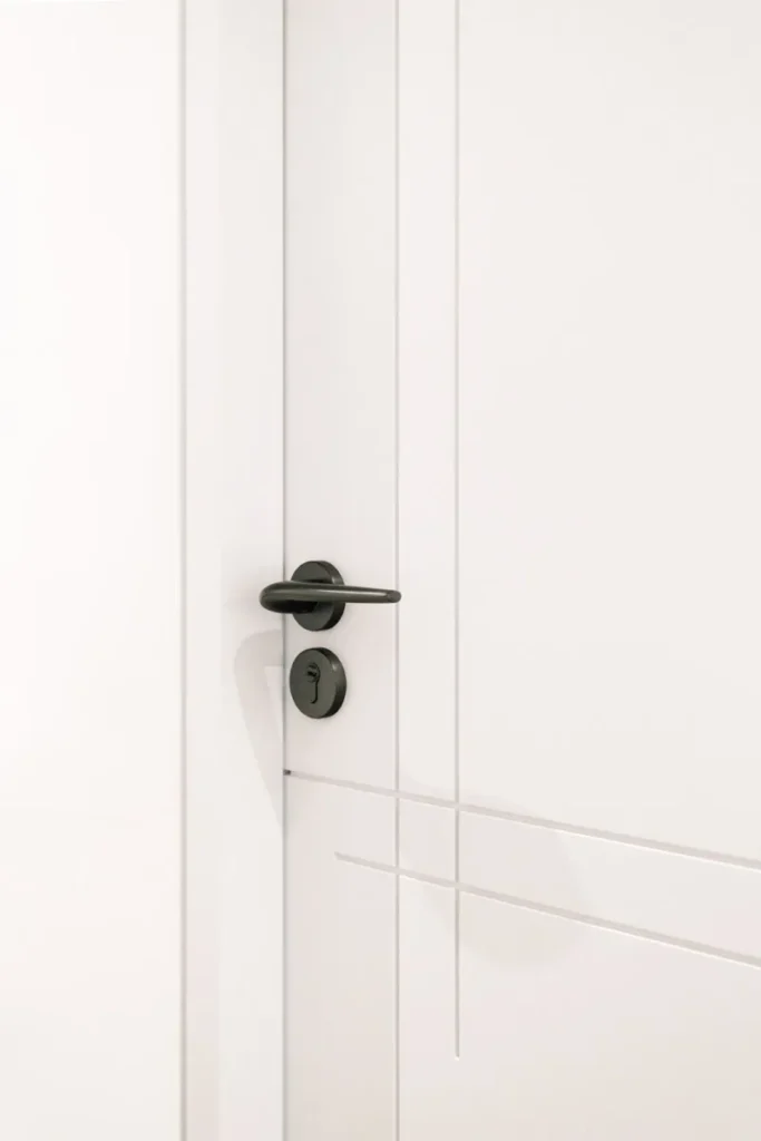 Simplicity meets style in this Rebel Arkitekt-designed door detail, featuring a modern matte black handle contrasting with clean white lines, reflecting the home's minimalist and serene aesthetic.