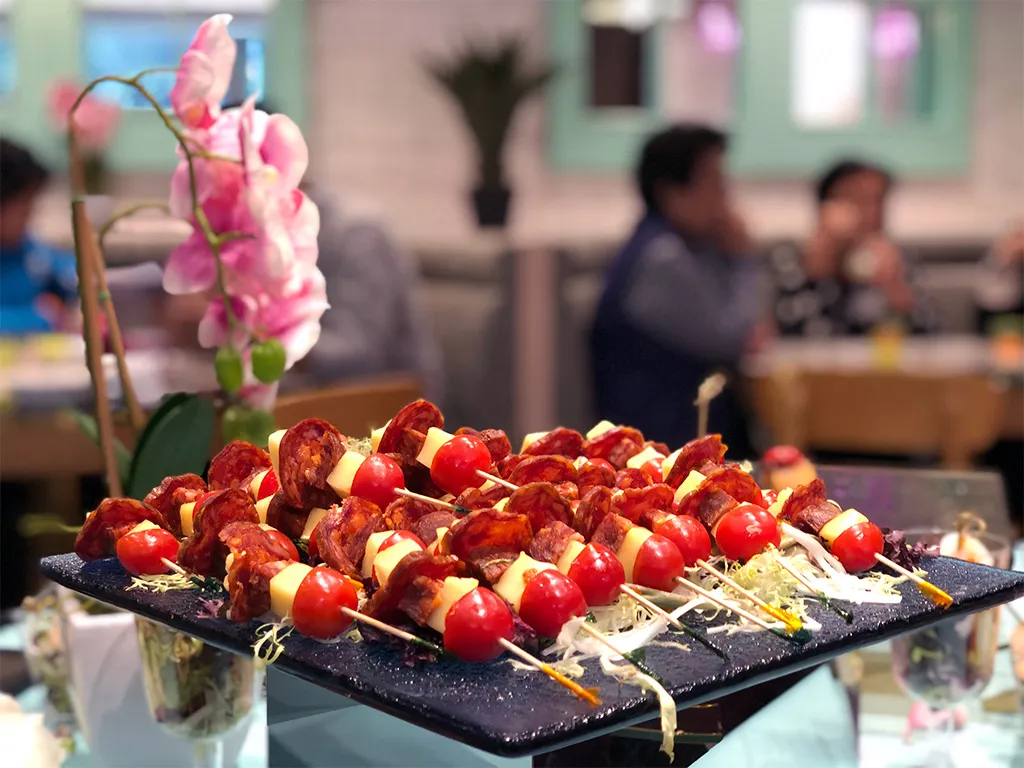 Appetizing presentation of M Kitchen's Asian fusion cuisine with chorizo and cheese skewers, enhanced by the restaurant's inviting ambience designed by Rebel Arkitekt.