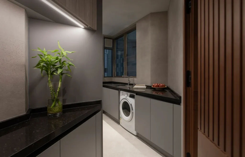 Streamlined kitchen space designed by Rebel Arkitekt, blending functionality with sleek aesthetics, featuring dark countertops, integrated appliances, and a touch of greenery to soften the modern look.