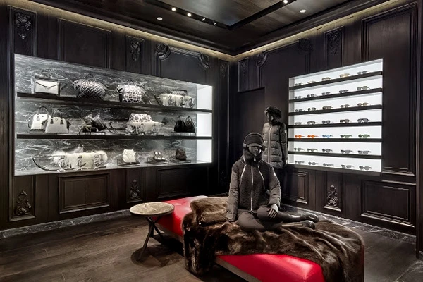 Luxury ski shop interior with black walls, showcasing handbags, sunglasses, and mannequin dressed in winter gear.