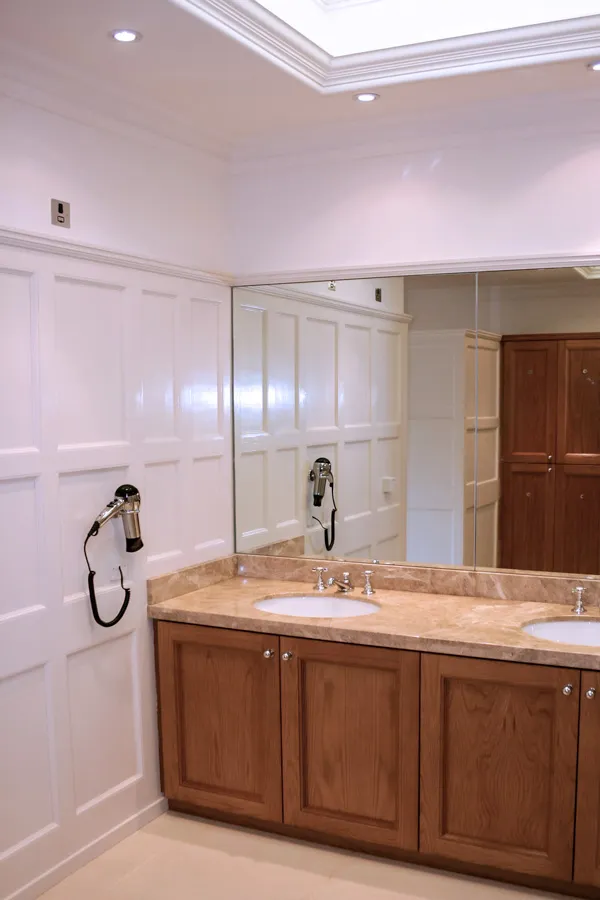 Modern changing room with marble countertop, wooden cabinets, and white paneling.