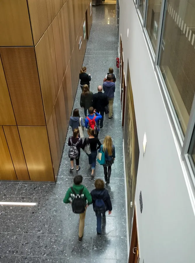 Modern veterinary school atrium with a polished granite floor, minimalist seating, and stained glass panels. A statue of founder William Dick presides in the naturally-lit space, showcasing a fusion of heritage and contemporary design.