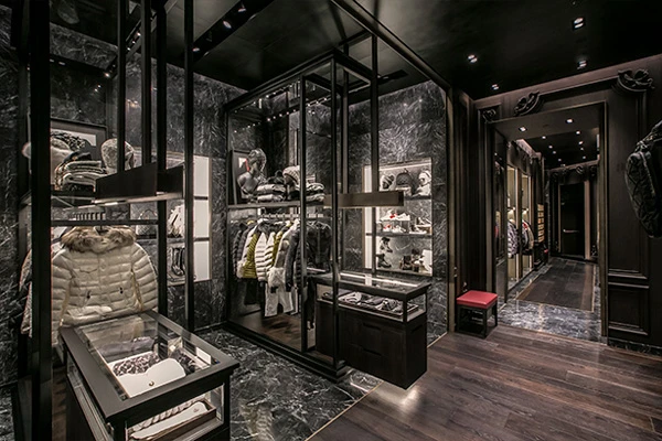 Chic ski shop interior with dark marble floors and walls, displaying a variety of jackets and accessories under soft lighting.