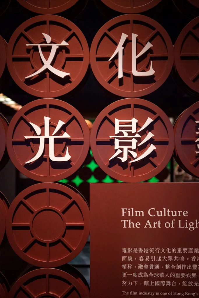 Artistic wall exhibit highlighting the significance of the film industry in Hong Kong, featuring stylized Chinese characters and vintage reels, celebrating the art of cinematography and storytelling.