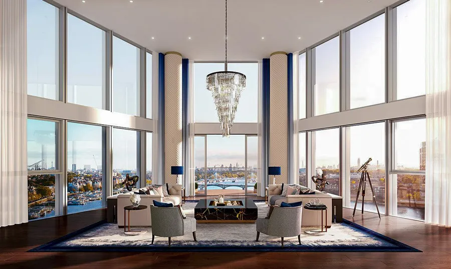 Luxurious double-height living room in a high-rise apartment with floor-to-ceiling windows providing an expansive view of the London cityscape, furnished with stylish seating, an elegant crystal chandelier, and finished with a deep blue rug and accent decor, all bathed in natural light.