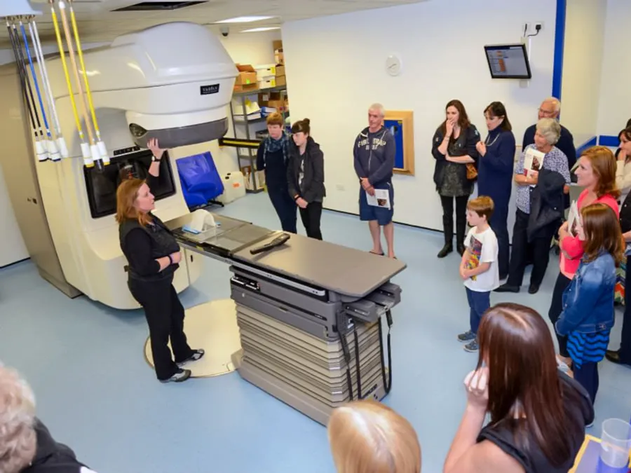 Group tour of veterinary MRI suite with a technician explaining the imaging equipment to attentive visitors.