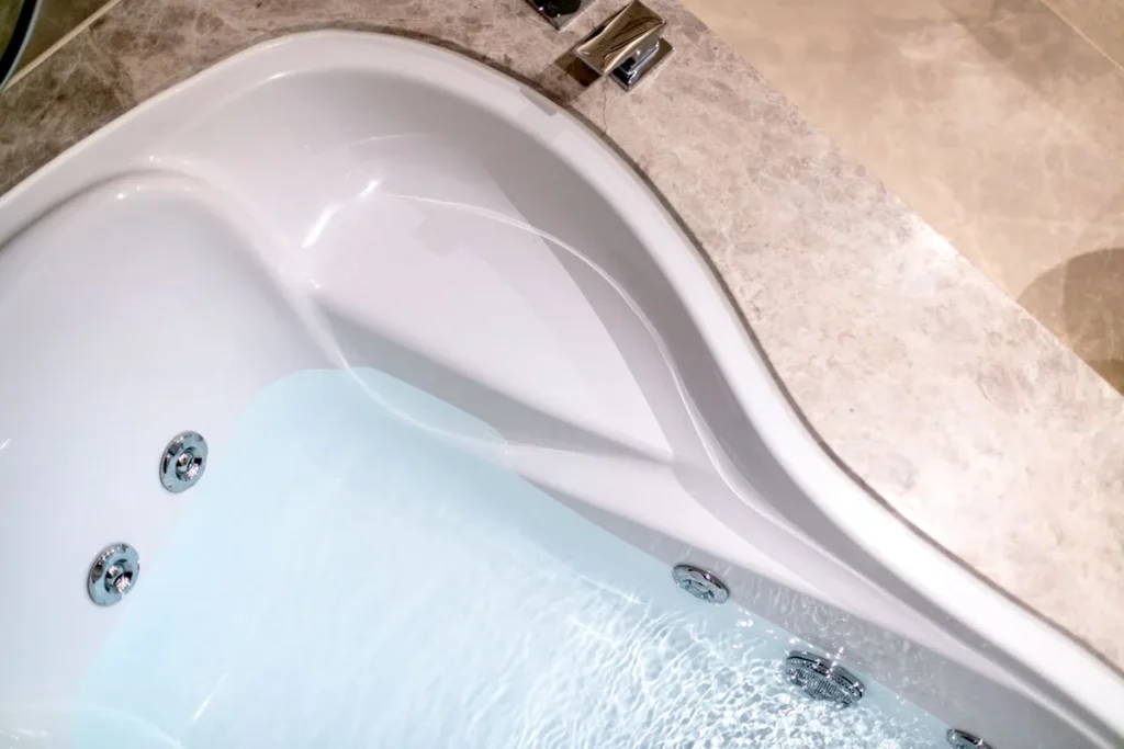 Elegantly designed jacuzzi bathtub with running water, set against light beige Italian tiles, a detail from Rebel Arkitekt's luxurious and soothing bathroom concept.