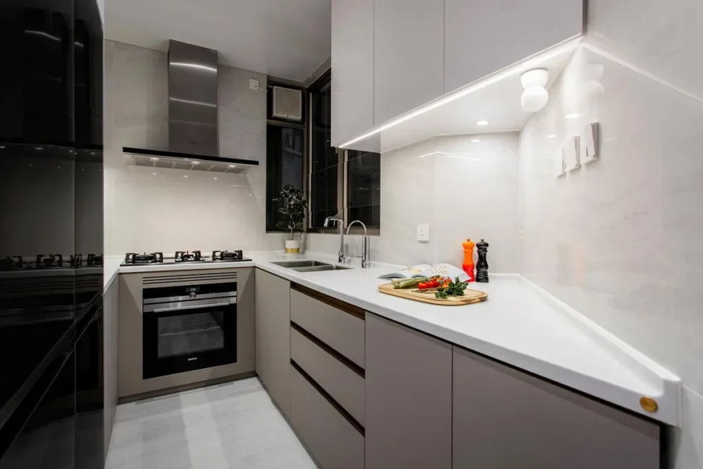 A modern kitchen with sleek cabinetry, under-cabinet lighting, and high-end appliances, designed by Rebel Arkitekt to offer both functionality and style in a compact space.