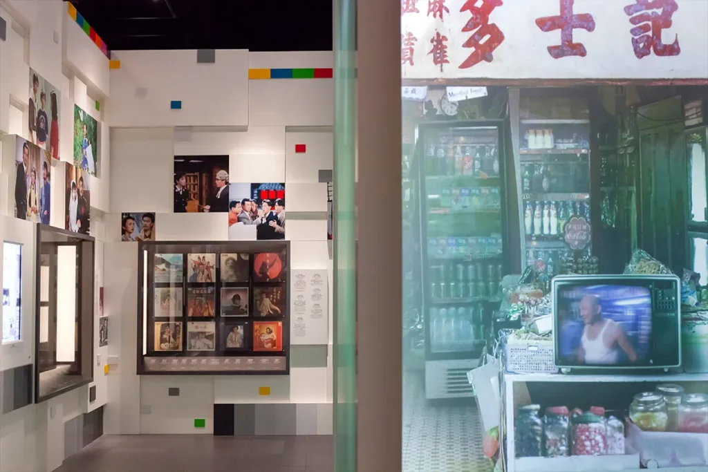 A vivid contrast between a modern, blocky white wall adorned with colorful film posters, and a traditional Hong Kong-themed video room with cultural memorabilia, overseen by a project managed by Rebel Arkitekt.