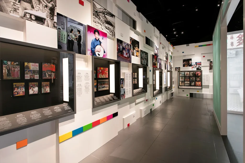 An exhibition wall presents a collage of colorful cinematic memories and iconic television moments, highlighted by assorted display cases, complementing the visual narrative of Hong Kong's entertainment history.