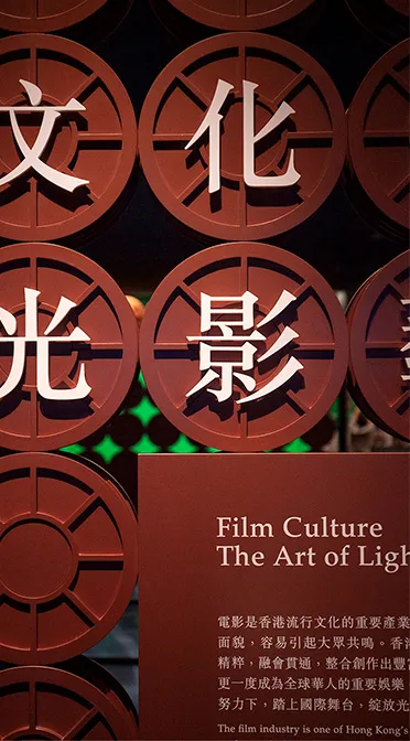 Artistic wall exhibit highlighting the significance of the film industry in Hong Kong, featuring stylized Chinese characters and vintage reels, celebrating the art of cinematography and storytelling.