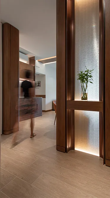 Warmly lit entrance vestibule featuring custom woodwork and a serene, illuminated alcove with greenery, designed by Rebel Arkitekt to offer a tranquil welcome while optimising space.