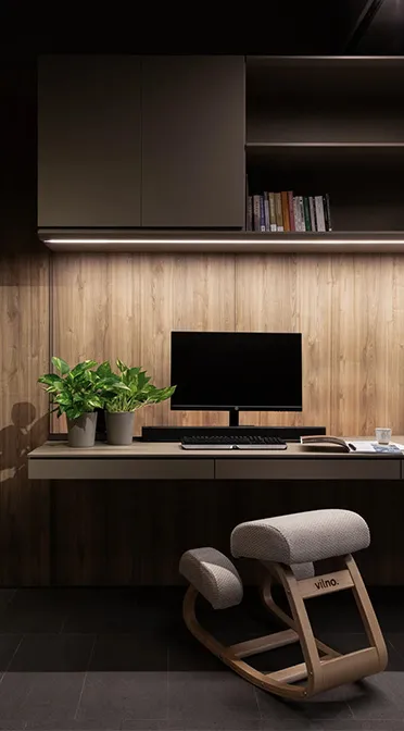 Elegantly designed Rebel Arkitekt workspace featuring a wall-mounted desk with ergonomic kneeling chair, ambient lighting, and lush greenery enhancing the minimalist office aesthetic.