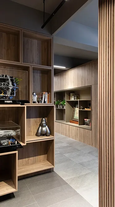 Modern office foyer showcasing custom shelving with accent pieces, featuring wooden textures and sleek lighting that highlight the display and walkway.