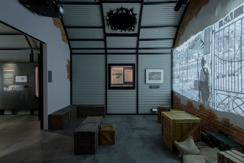 Gallery depicting wartime destruction with a bomb-damaged roof at the Hong Kong Museum of Coastal Defence, showcasing the impact of Japanese aggression during WWII.