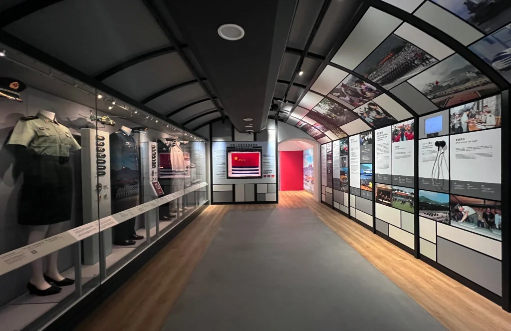 Display featuring Chinese military uniforms, insignias, and historical panels in the Hong Kong Museum of Coastal Defence