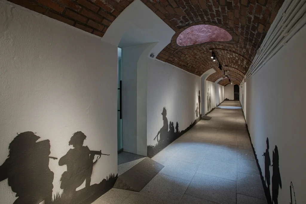 Brick-vaulted hallway with shadow silhouettes of soldiers on the walls at the Hong Kong Museum of Coastal Defence