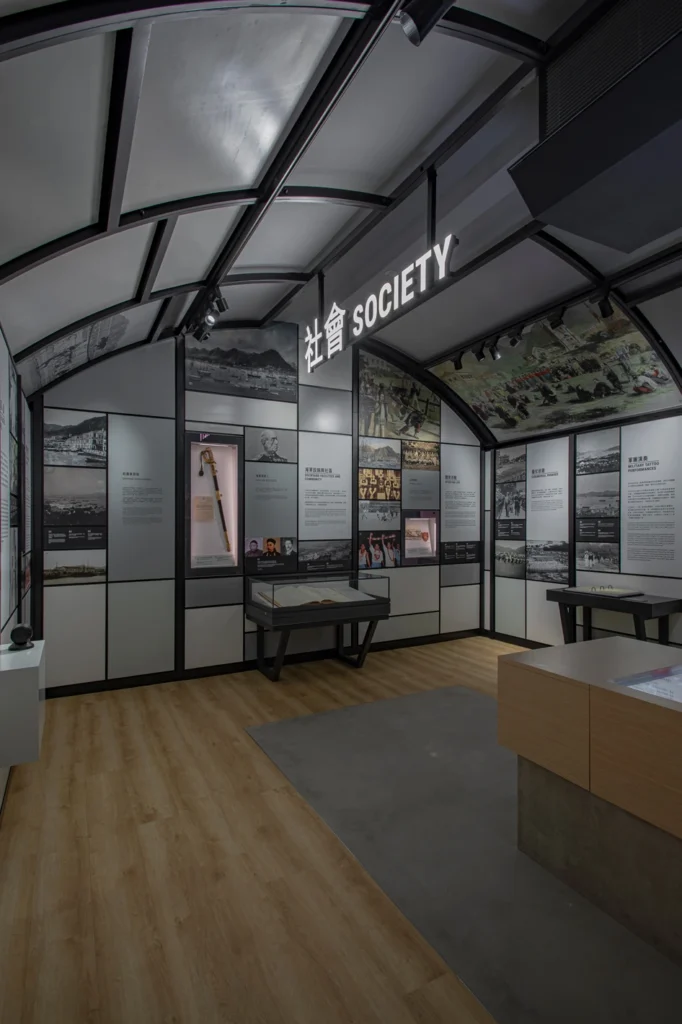 The exhibit showcases historical artifacts with interpretive panels, modern lighting, and sleek display cases in a minimalist setting