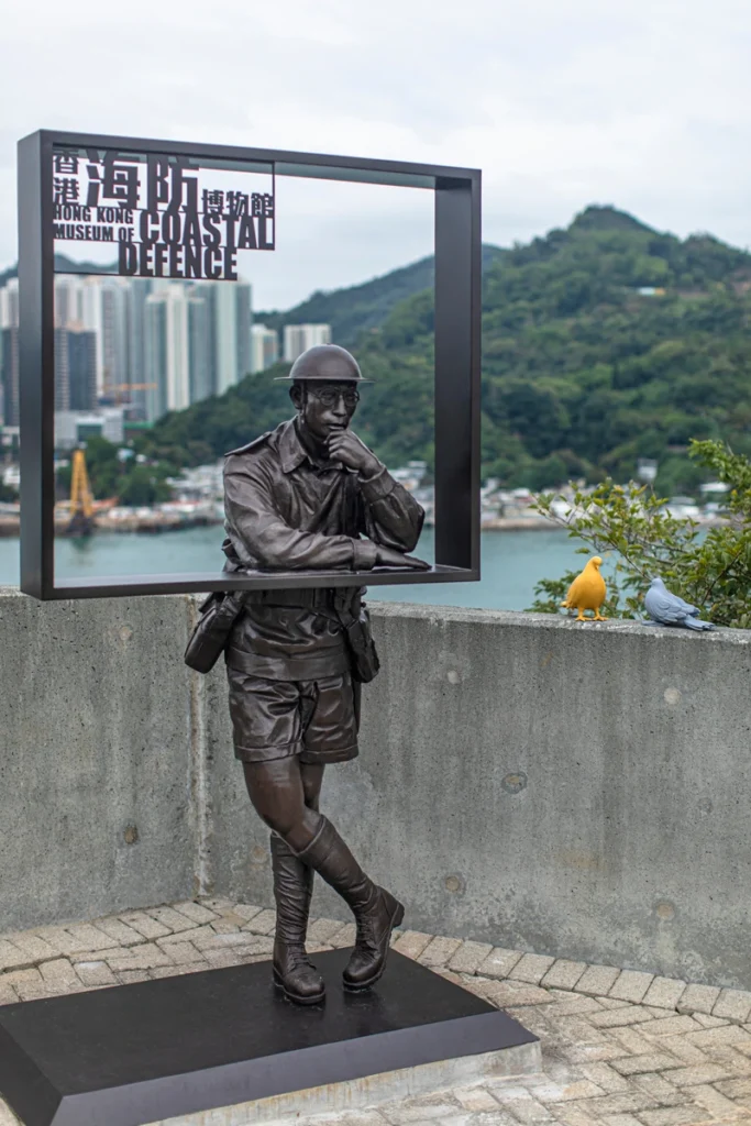 Soldier sculpture at the Hong Kong Museum of Coastal Defence, symbolizing military history against a scenic city and hillside backdrop.