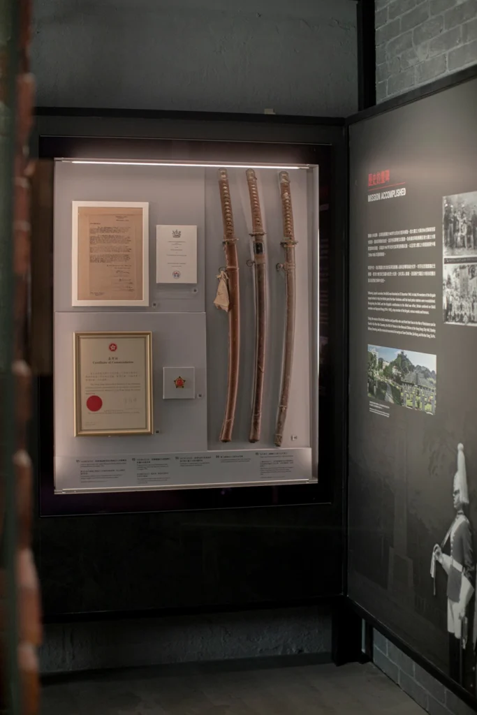 Display case with historic Japanese swords, official commendations, and documents at the Hong Kong Museum of Coastal Defence