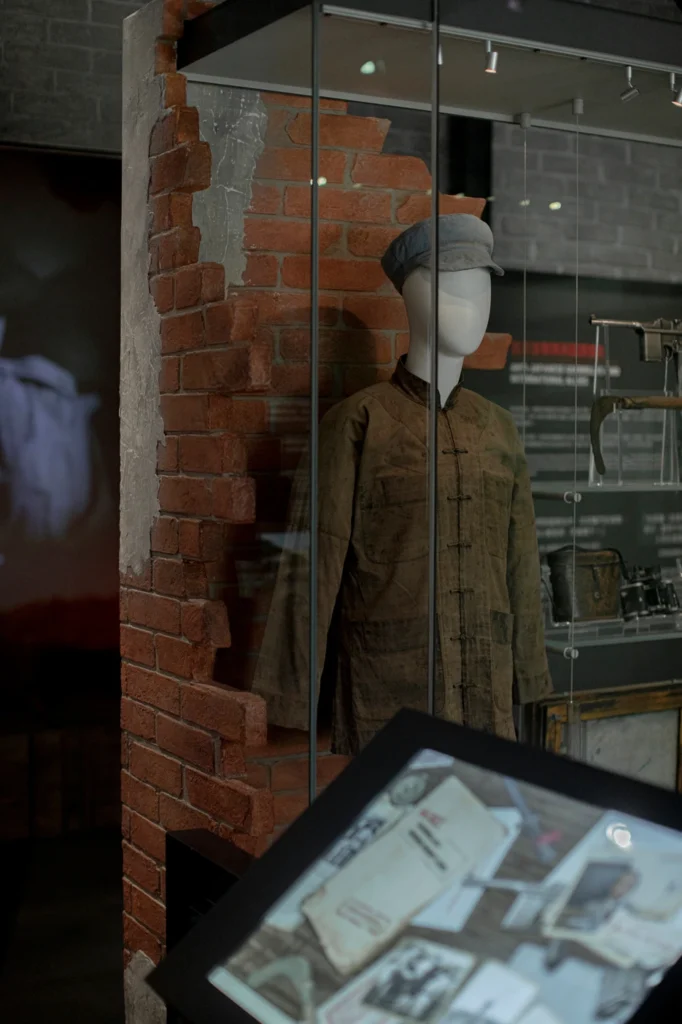 Exhibit featuring a military uniform and artifacts in a glass display case at the Hong Kong Museum of Coastal Defence