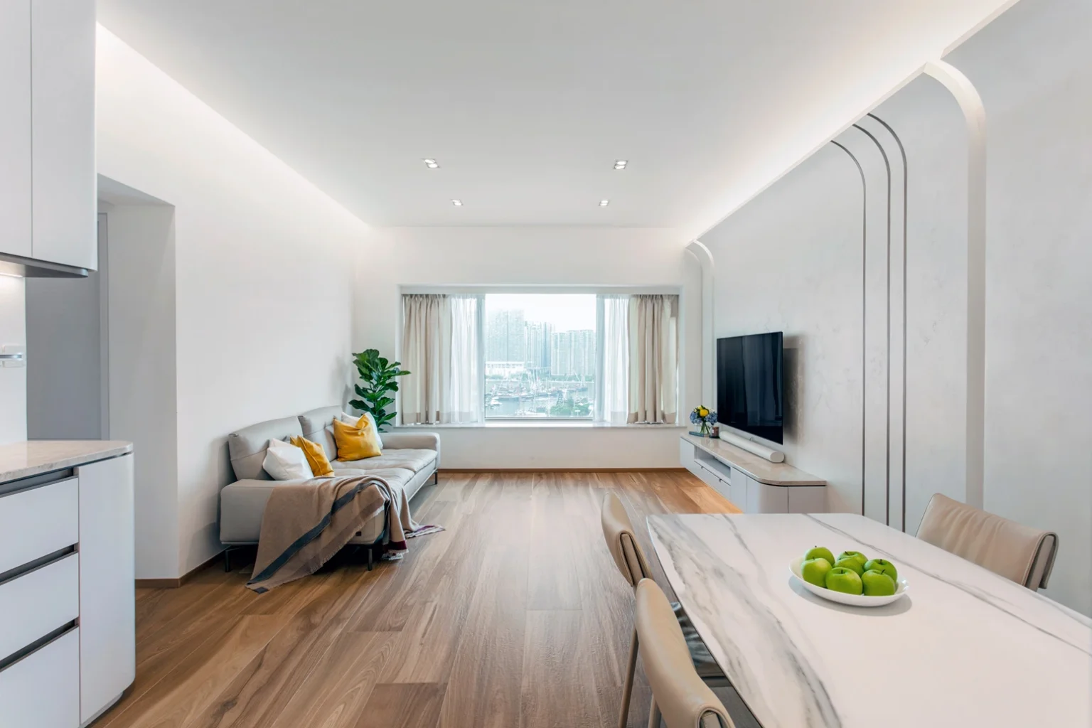 Spacious and airy West Kowloon apartment living area designed by Rebel Arkitekt, with bespoke curved wall features, ambient lighting, and Italian timber-patterned flooring, all enhancing the clean, Zen-inspired aesthetic.