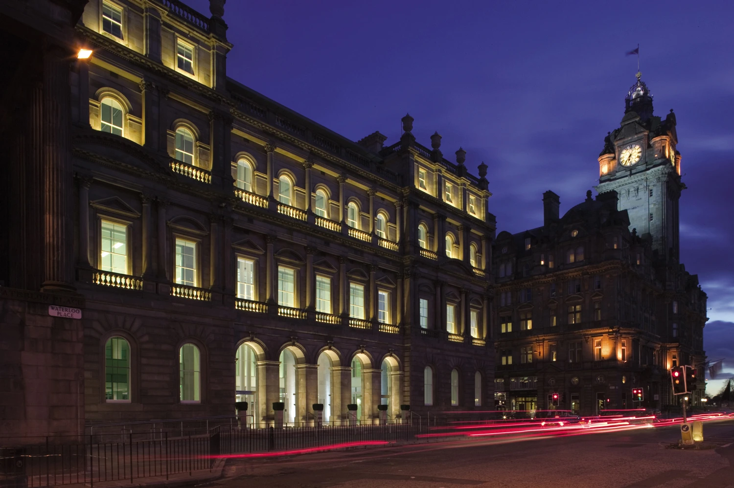 Classical architecture of Waverleygate building at night with illuminated windows and clock tower, Edinburgh.