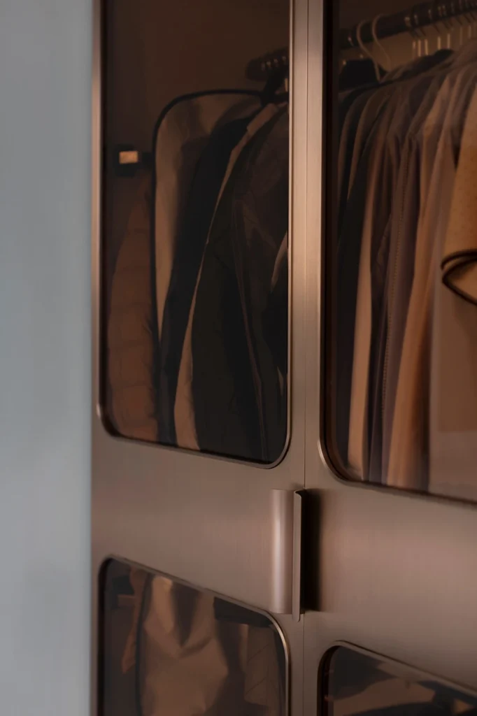 close-up of wardrobe with smoked glass panels and bronze handles